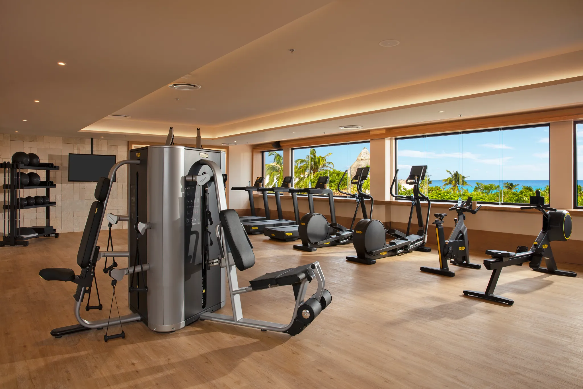 Modern fitness center with cardio machines and ocean views at Dreams Aventuras Riviera Maya.