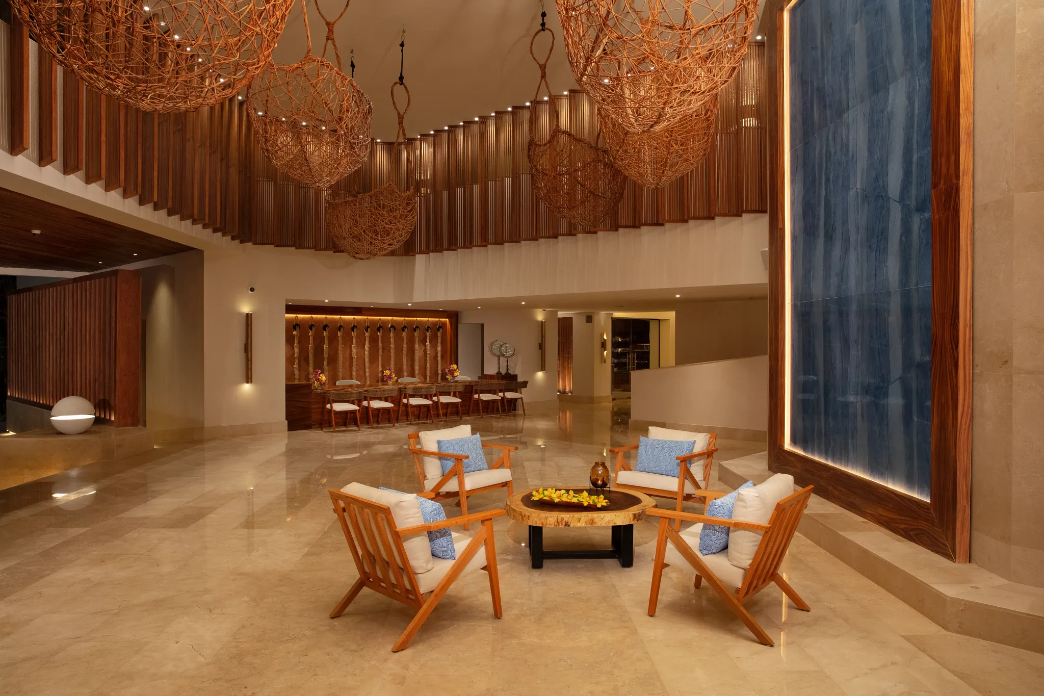 Elegant resort lobby with seating area, natural wood decor, and hanging art installations at Dreams Aventuras Riviera Maya.