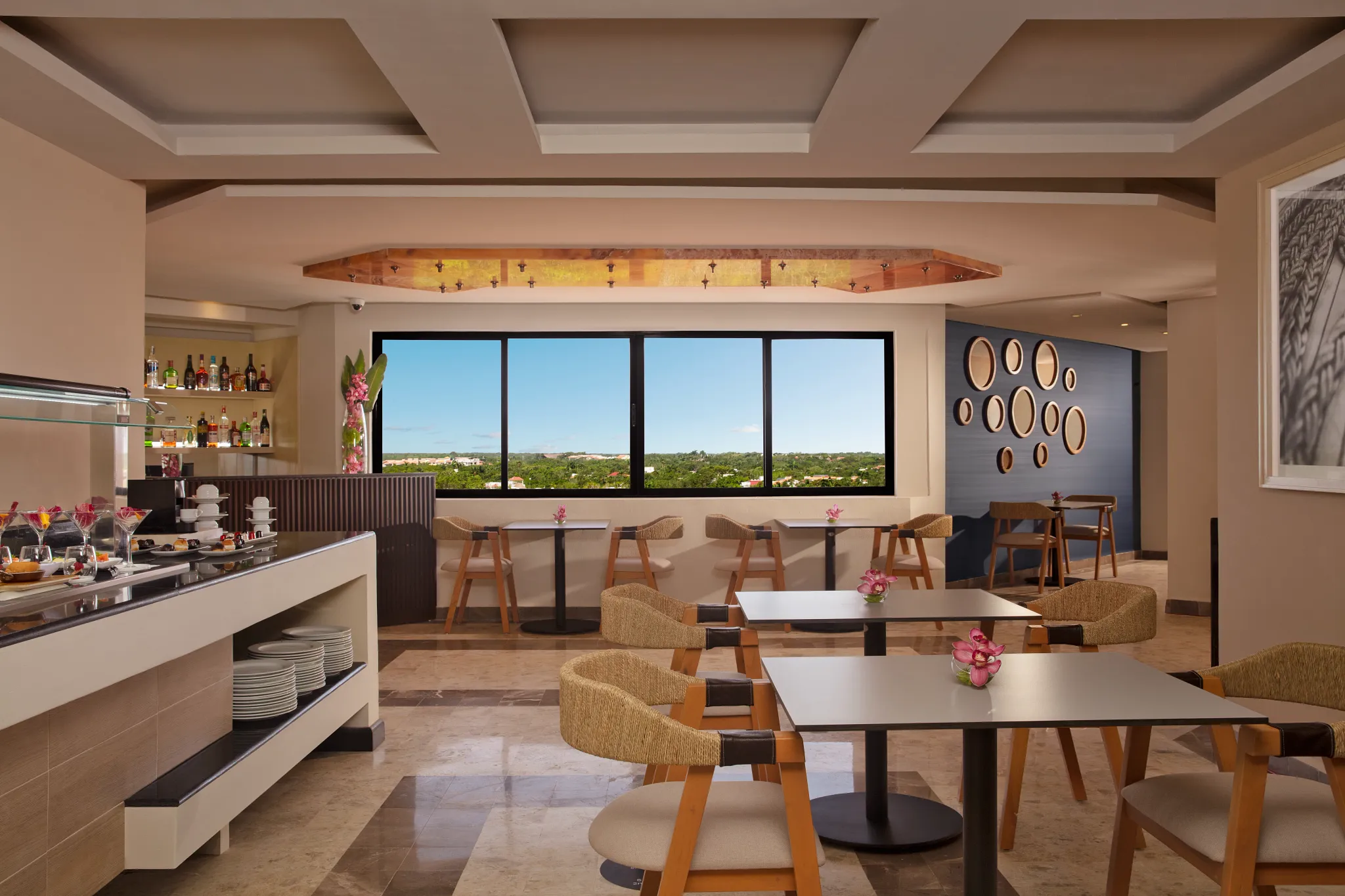 Indoor lounge dining space with modern seating and large windows at Dreams Aventuras Riviera Maya.