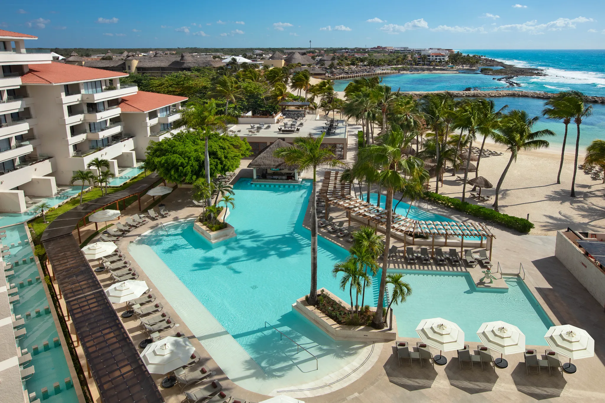 Large main pool with swim-up areas and lounge seating at Dreams Aventuras Riviera Maya.