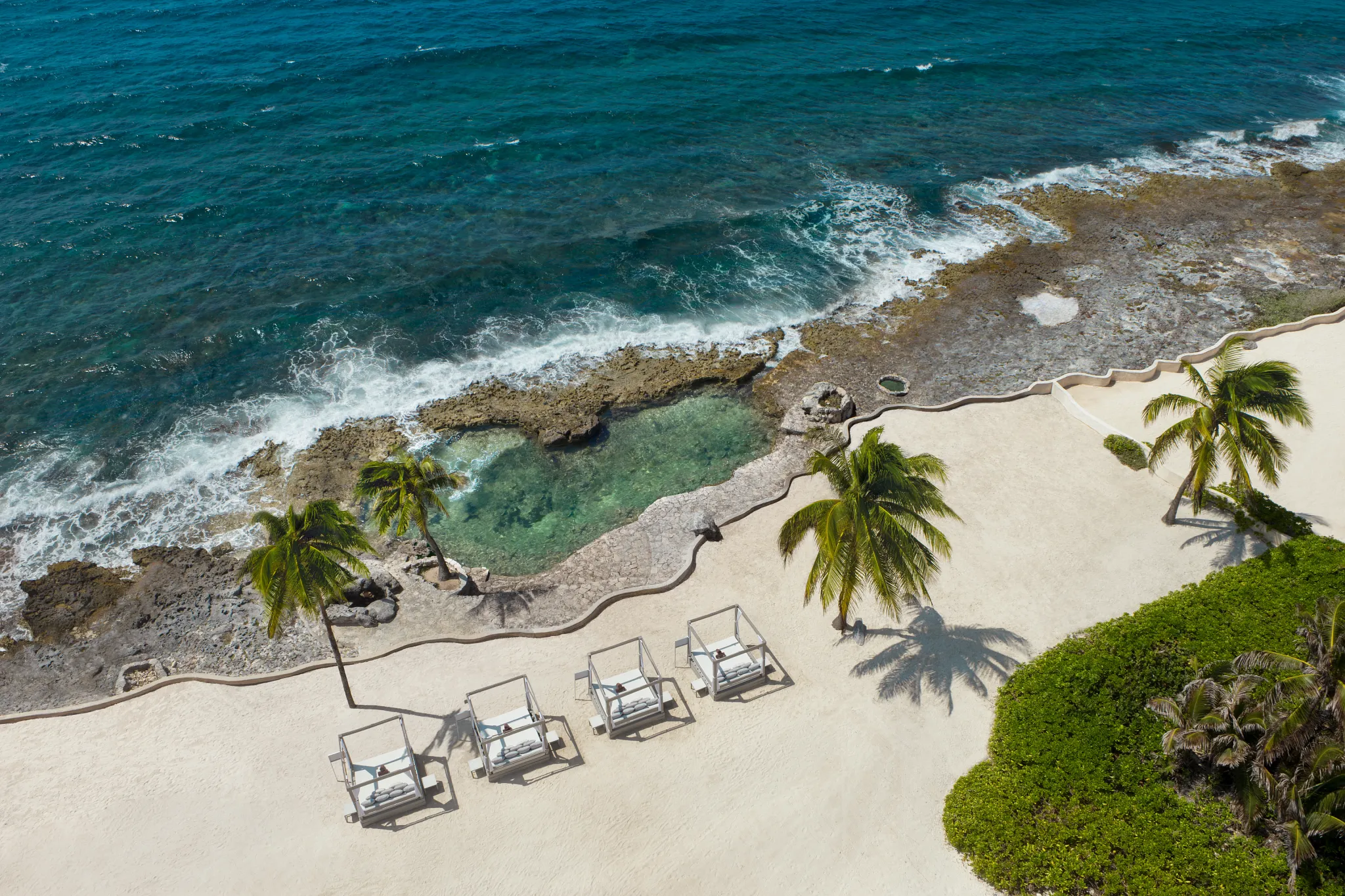 Natural ocean-fed pool with rocky shoreline and clear turquoise water at Dreams Aventuras Riviera Maya.