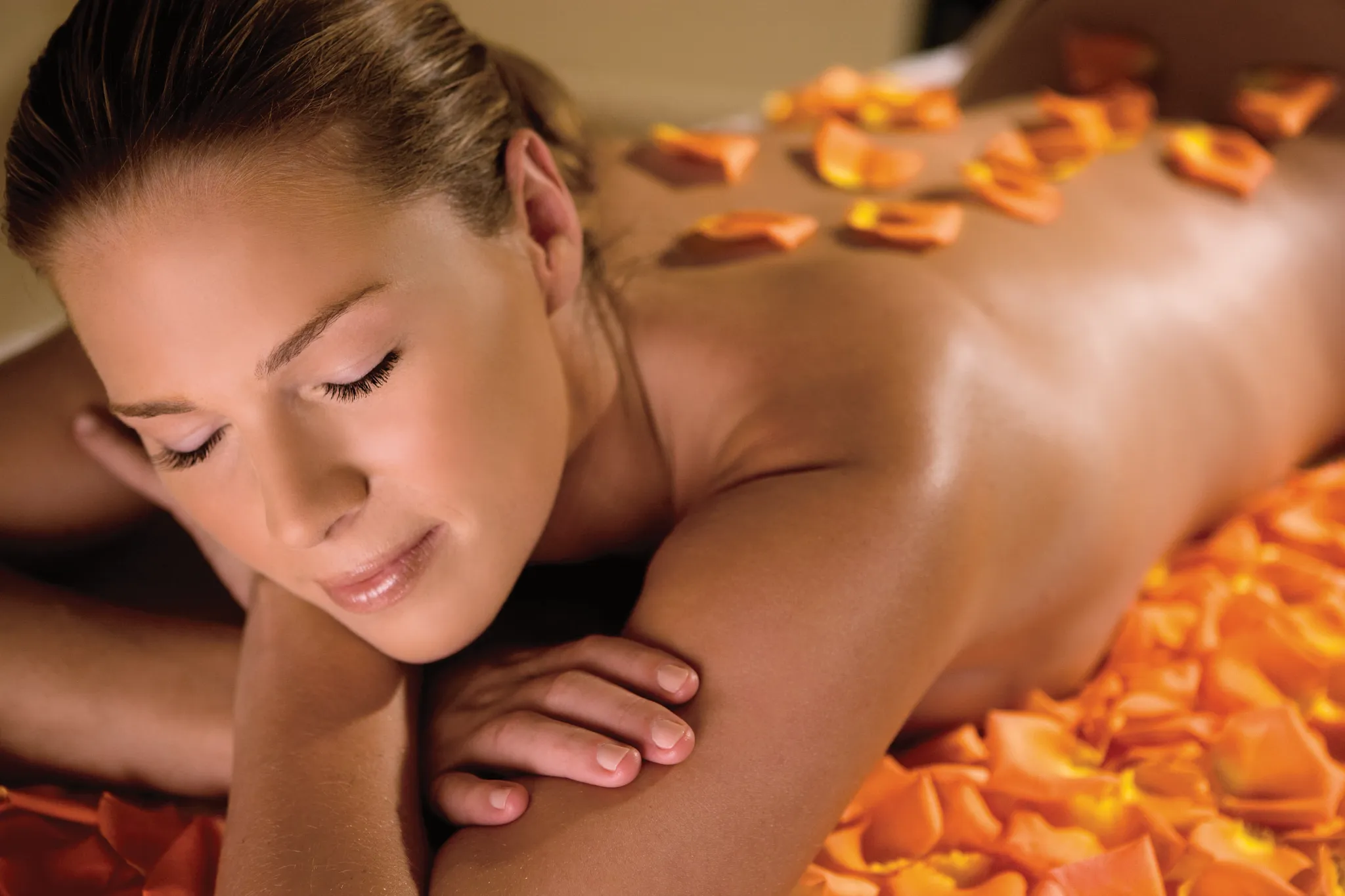 Woman enjoying a relaxing massage with flower petals at Dreams Aventuras Riviera Maya spa.