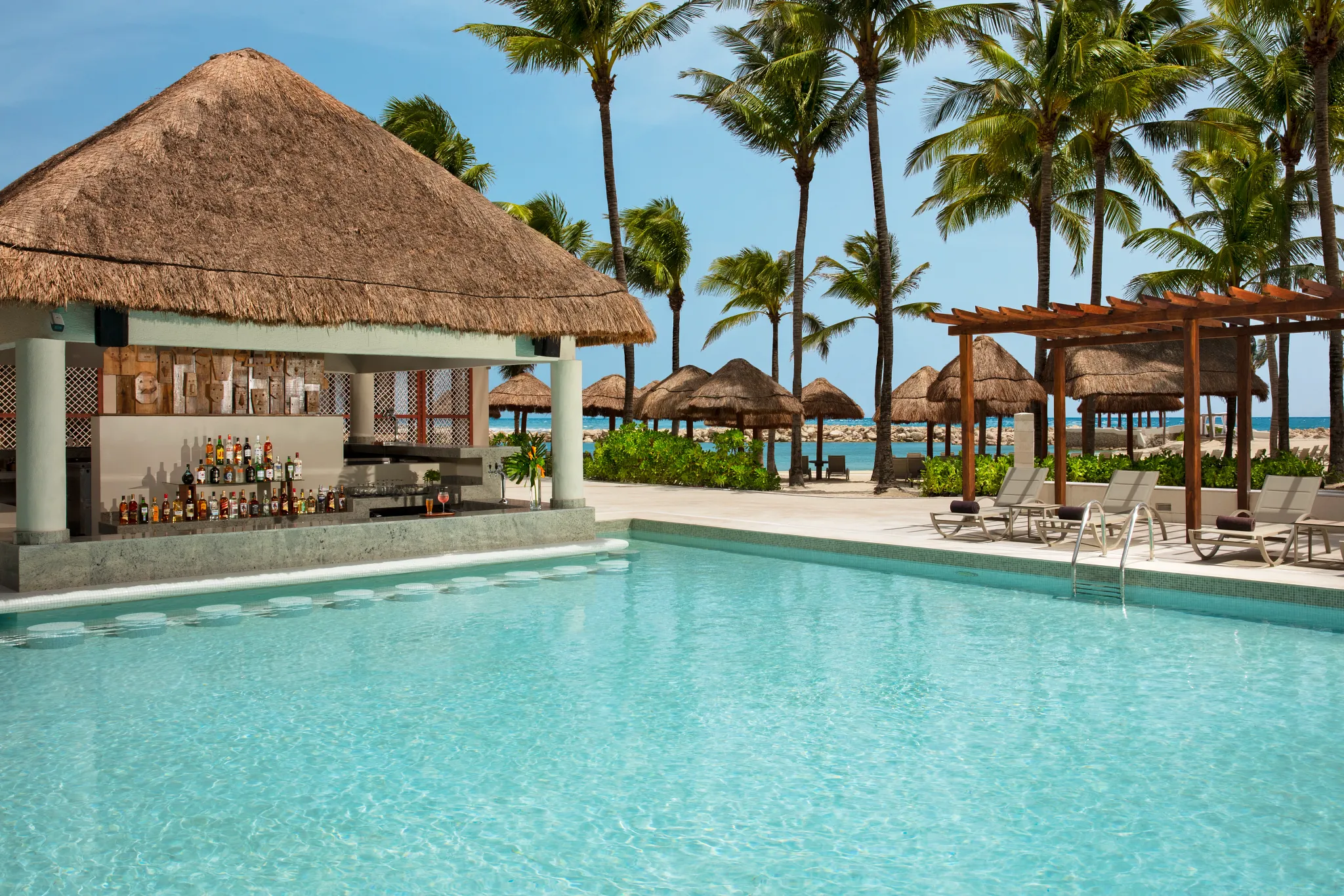 Sugar Reef pool bar at Dreams Aventuras Riviera Maya featuring a relaxed swim-up setting, tropical cocktails, and vibrant poolside atmosphere.